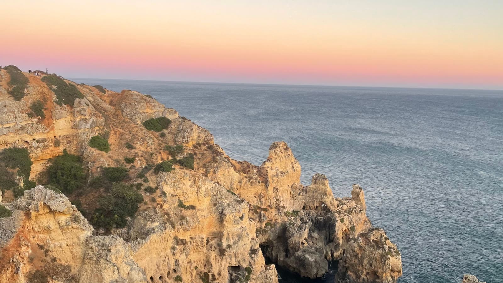 Golden limestone cliffs and sea stacks on the Algarve coast under a clear sky