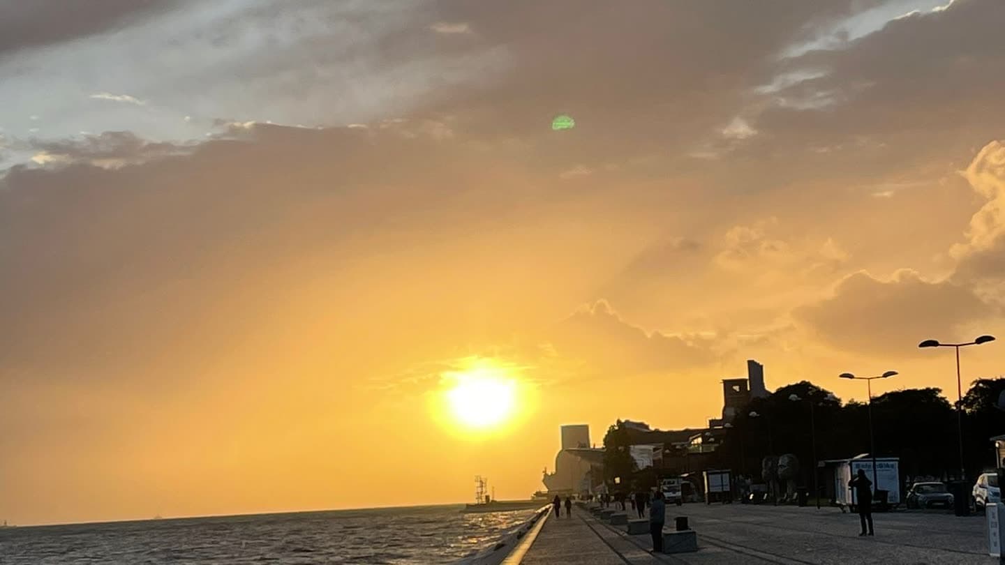 People walking a seafront promenade at sunset