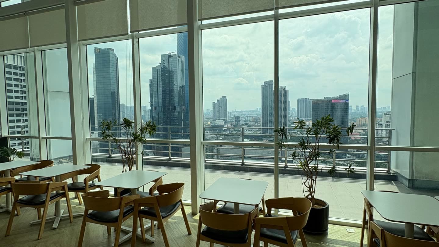 An empty co-working floor in Kuala Lumpur, desks running along a wall of windows above the city