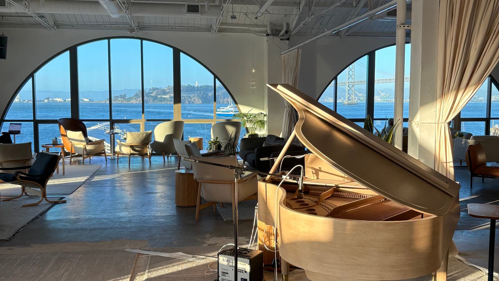 An empty office in San Francisco, tall arched windows looking out to the bay and the Bay Bridge