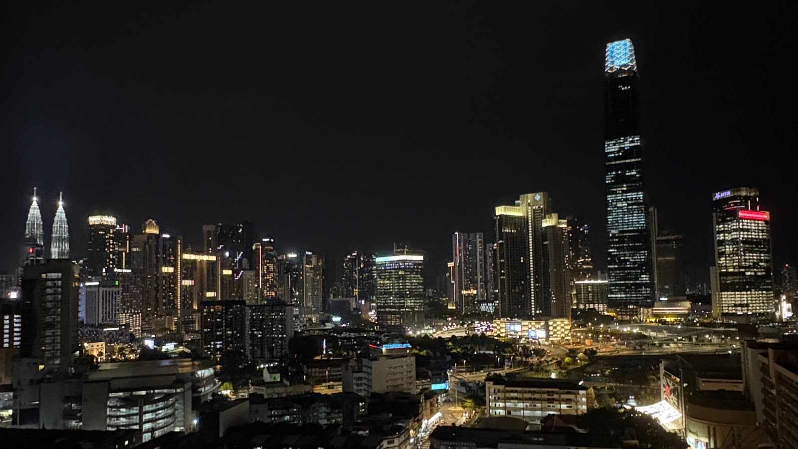 The Kuala Lumpur skyline lit up at night, the Petronas Towers and Merdeka 118 above the city