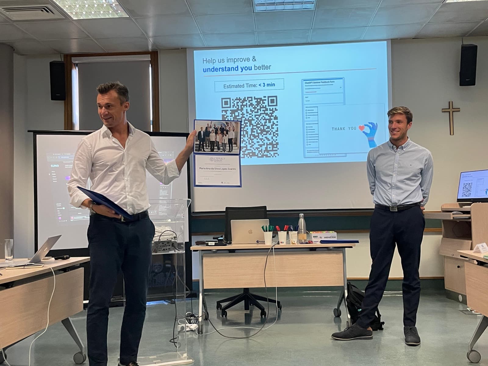 Marco Kohns presenting beside a projected slide in a seminar room, a colleague alongside him
