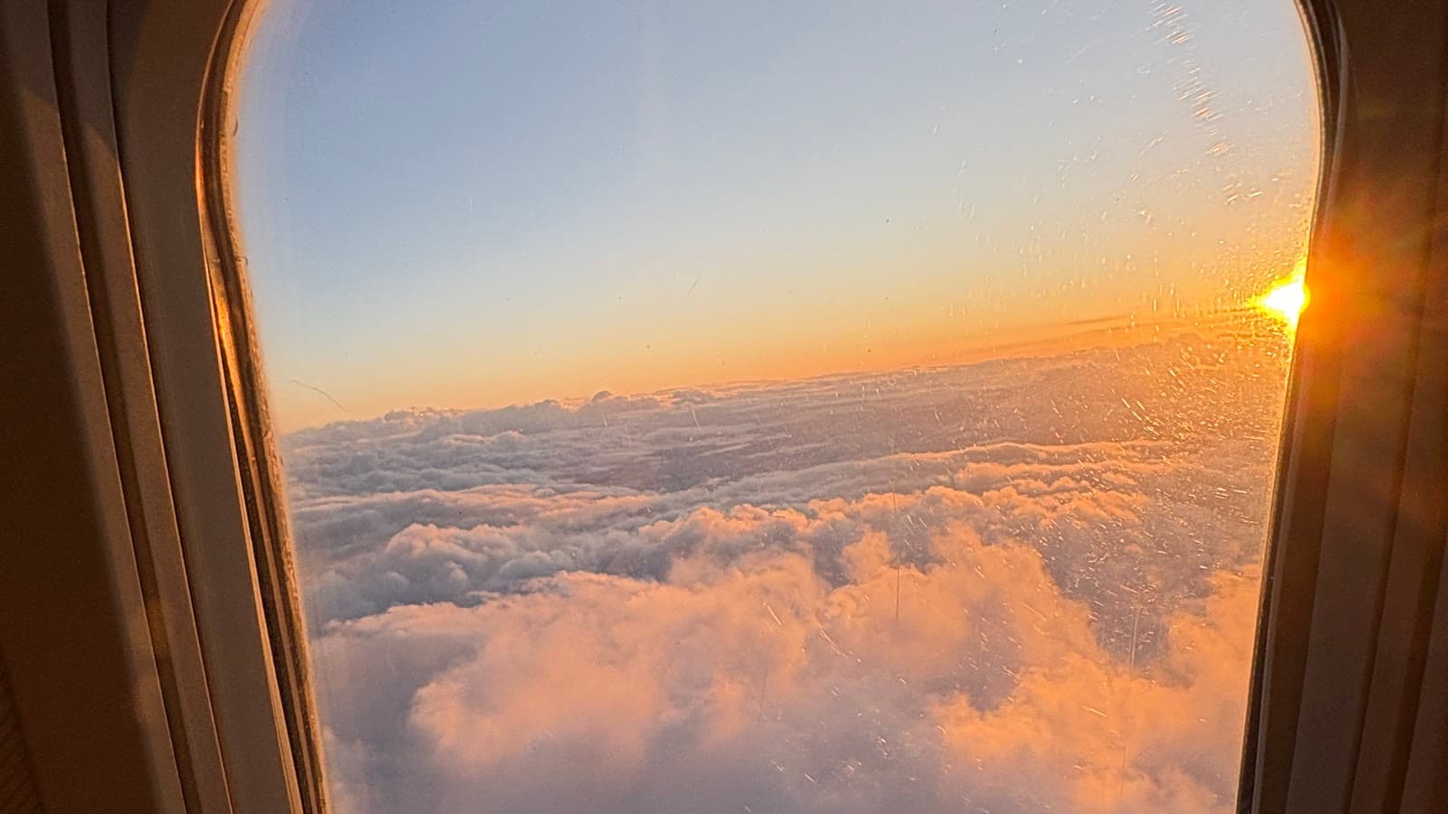 Sunrise breaking over a deck of cloud, seen from an aeroplane window
